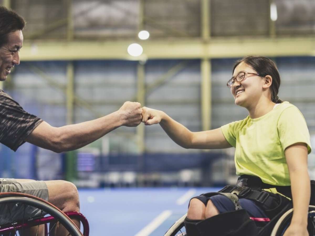 Two people in wheelchairs fist bumping.