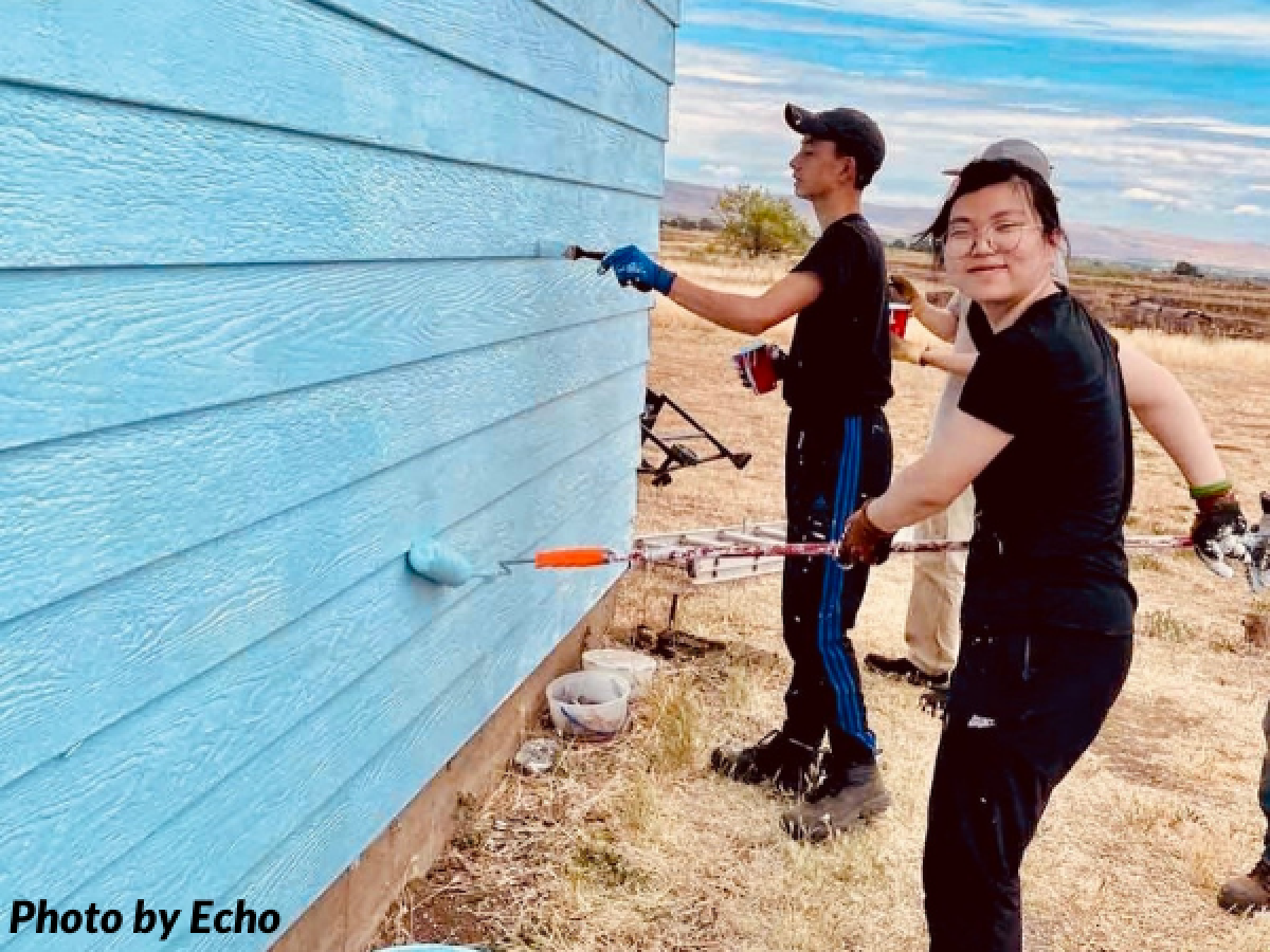 Three teens painting side of house blue